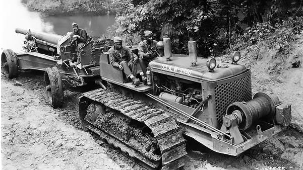 Three African American field artillery soldiers (from Battery F of the 349th Field Artillery, Fort Sill, Oklahoma) crossing a creek on a TD-18 diesel crawler tractor and 155 mm gun. The commanding officer of the 349th was Colonel A.L.P. Sands.